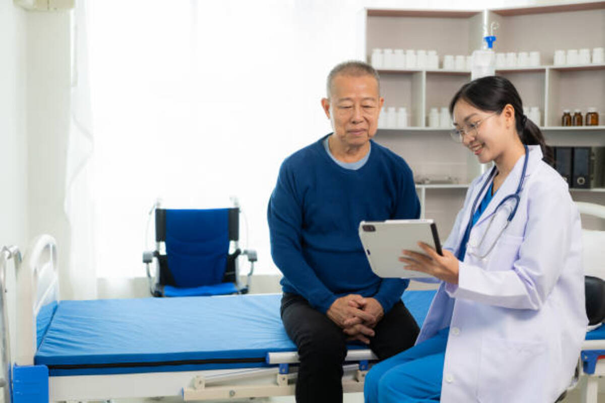 Doctor showing a tablet to a patient sitting on a hospital bed