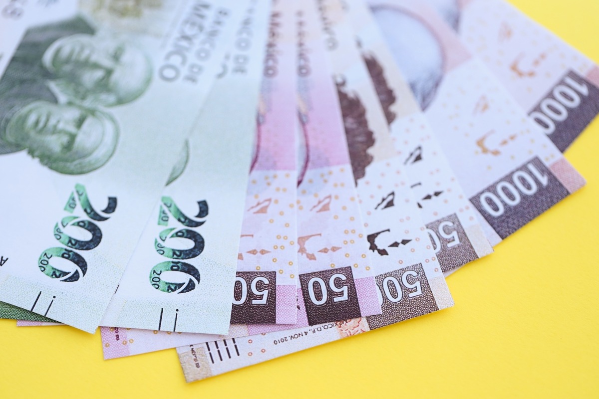 Mexican banknotes (200, 50, 1,000 pesos) fanned on yellow background.