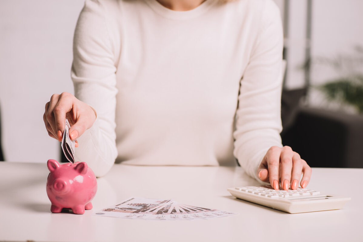 Woman Putting Money Into Piggy Bank