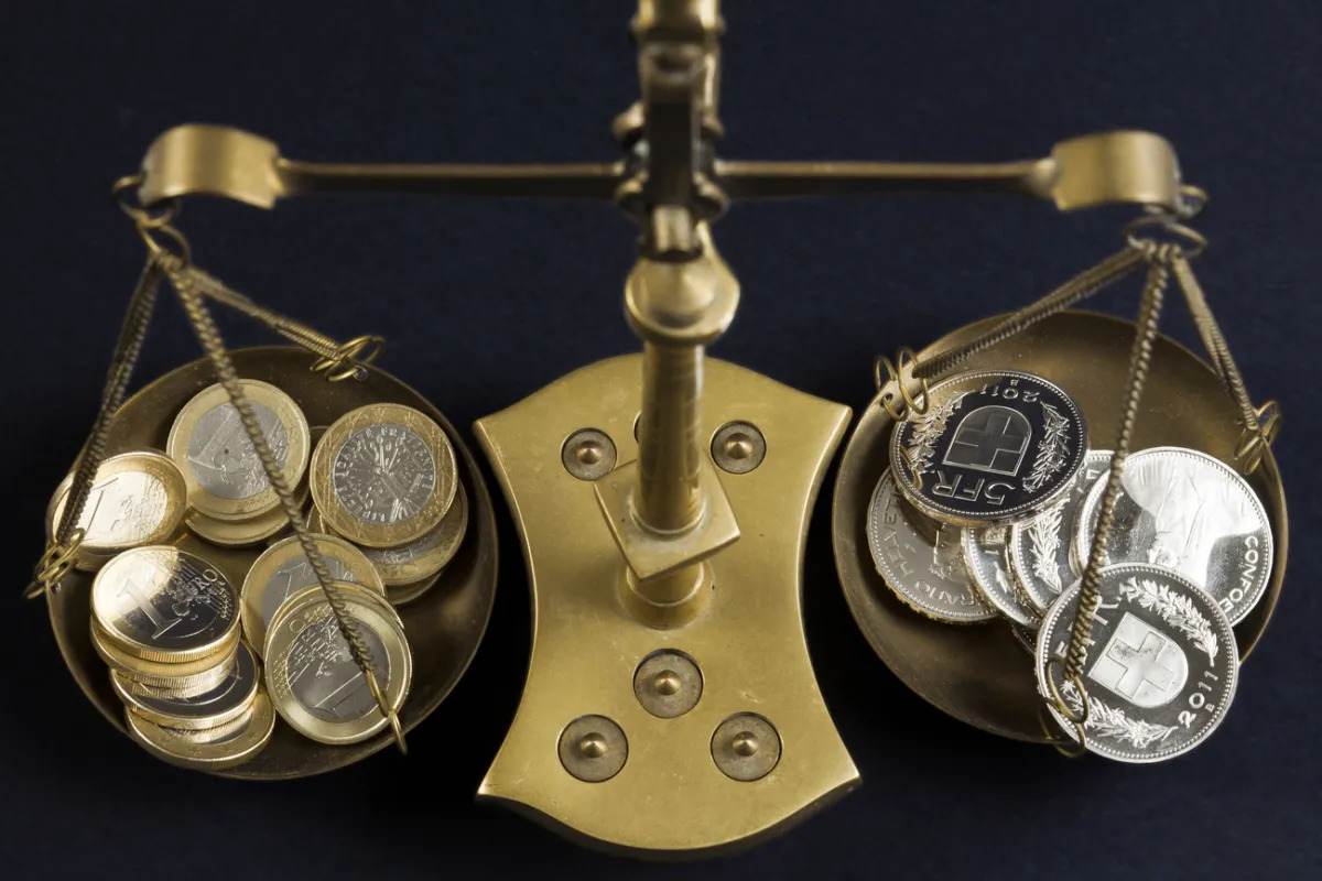 A balance scale with Euro and Swiss Franc coins, symbolizing currency value comparison.